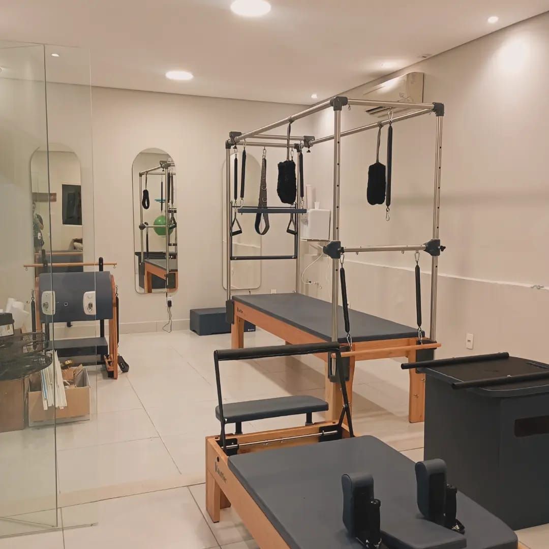 Visão ampla da sala de Pilates com Cadillac, Reformer e espelhos em arco